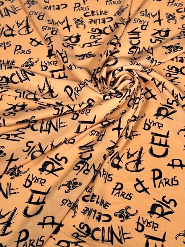 Beige fabric swirled in folds with a repeating black handwritten 'Paris' and 'CELINE' pattern.