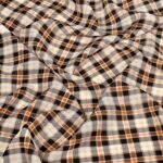 Close-up of plaid fabric in tan, black, and white with soft folds and texture.