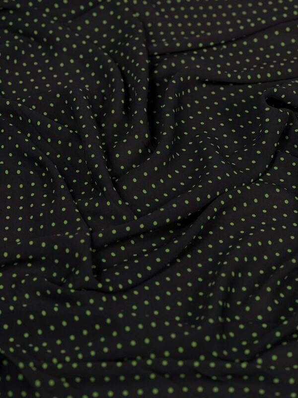 sph suknelinis audinys Black fabric with lime-green polka dots, softly draped and wrinkled.