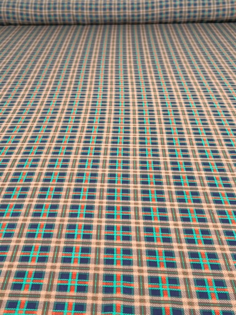 Close-up of a blue plaid fabric with teal and orange thin lines forming a grid pattern.