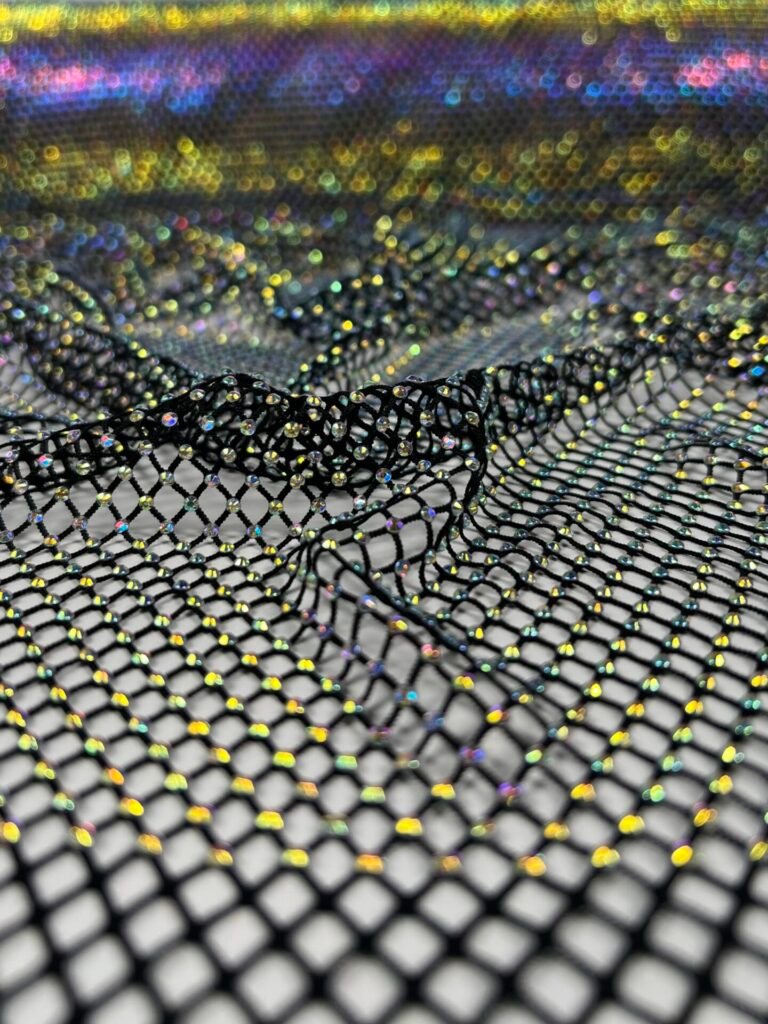 Close-up of black mesh fabric studded with tiny iridescent beads, with colorful bokeh lights in the background.
