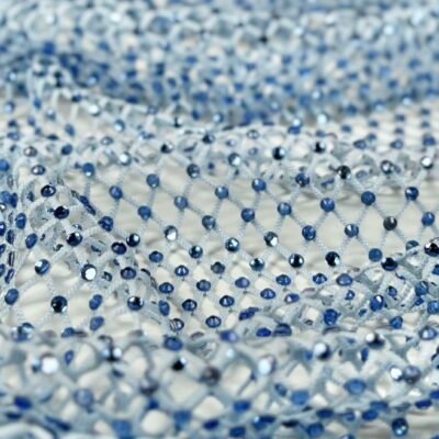 Close-up of a delicate net fabric adorned with small blue beads, creating a sparkling, textured pattern.