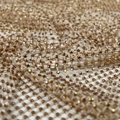 Close-up of gold sequin mesh fabric with tiny reflective beads in a grid pattern