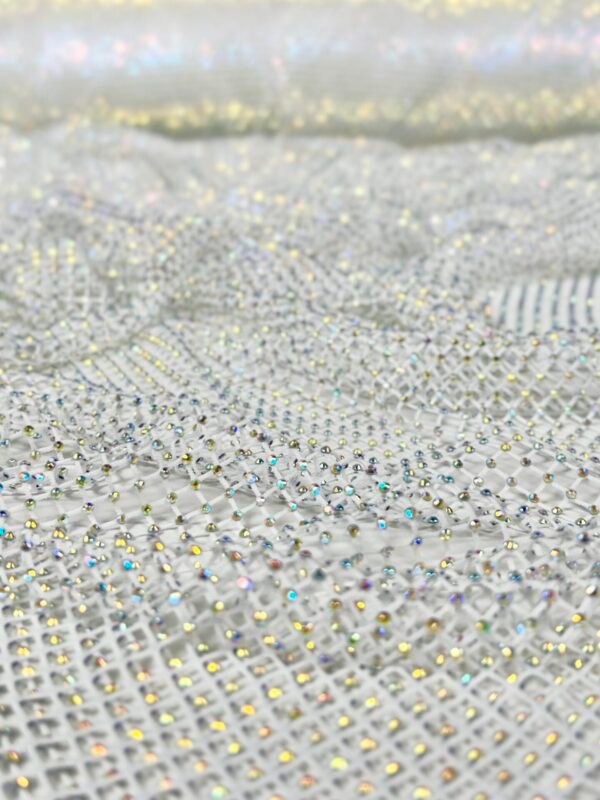 Close-up of sheer fabric covered in small iridescent rhinestones creating a sparkling pattern.