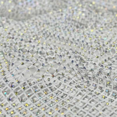 Close-up of white mesh fabric densely studded with tiny iridescent rhinestones, reflecting multicolored light.
