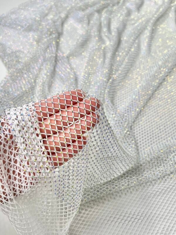 Hand holding shimmering silver mesh fabric with small rhinestones.