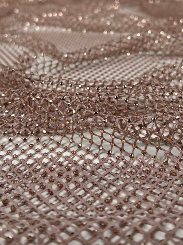 tinklelis su kristalais Close-up of brown mesh lace fabric with small reflective beads creating a delicate pattern.