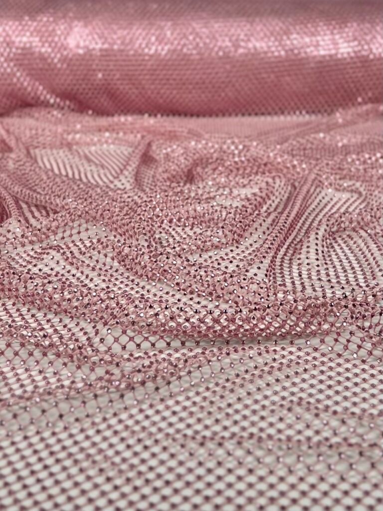 Close-up of pink mesh fabric embedded with tiny pink beads and subtle sparkles.